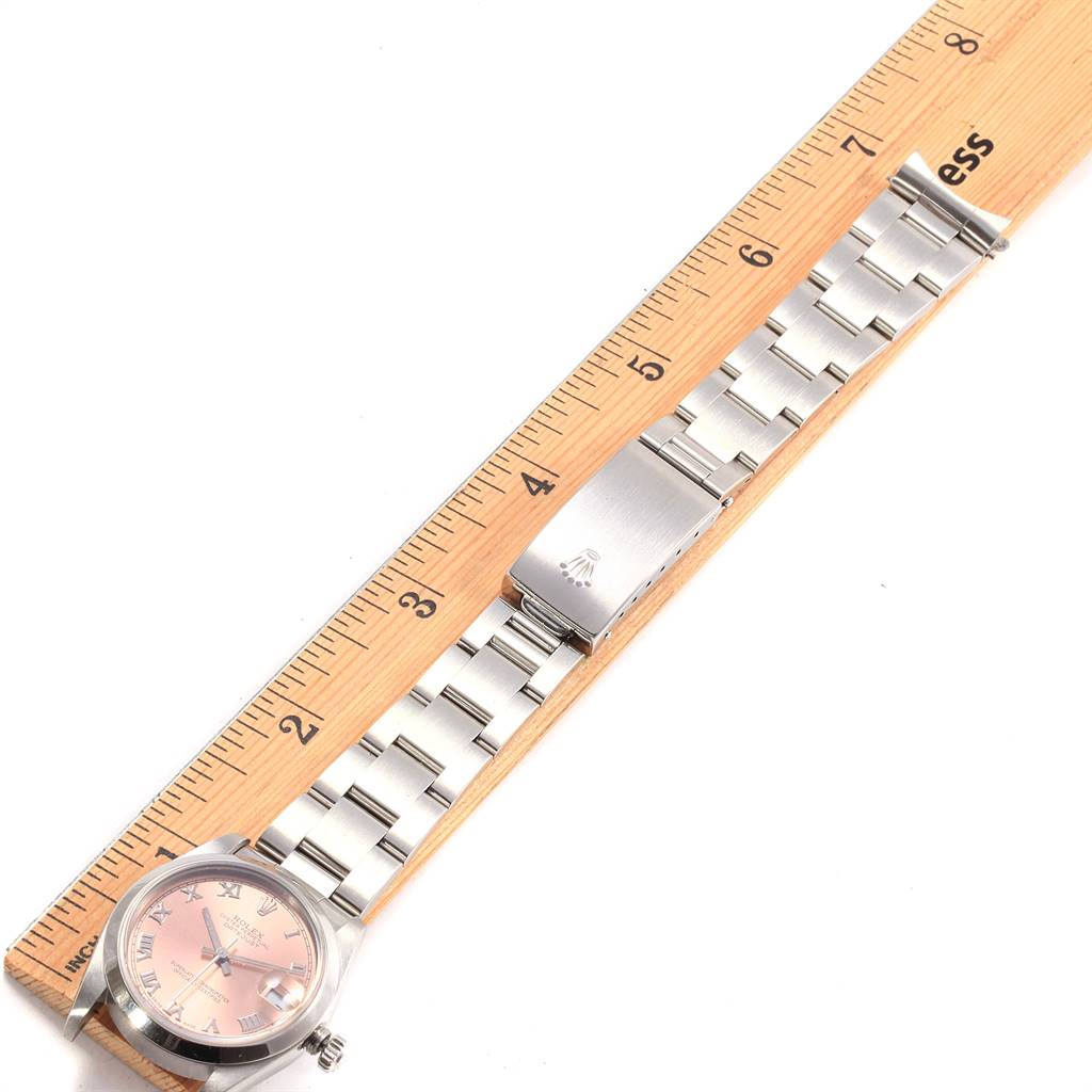 The image shows a flat lay view of a Rolex Mid-Size 78240 Women's Stainless Steel Pink Dial 78240 Women's Stainless Steel Pink Dial watch displaying the face, bracelet, and clasp beside a ruler for scale.