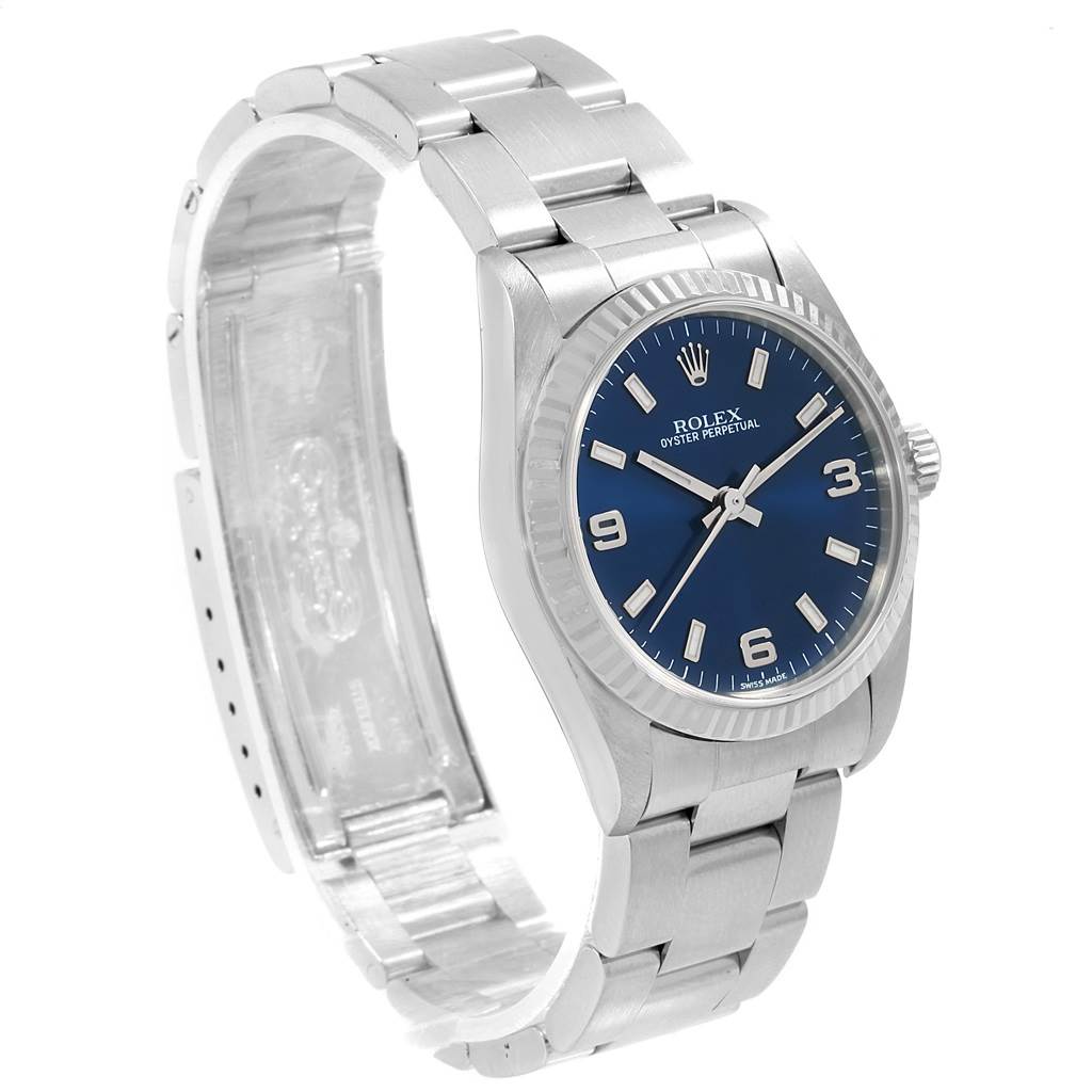 The image shows a Rolex Oyster Perpetual Mid-Size watch at an angled side view, displaying its blue dial, bezel, crown, case, and bracelet.