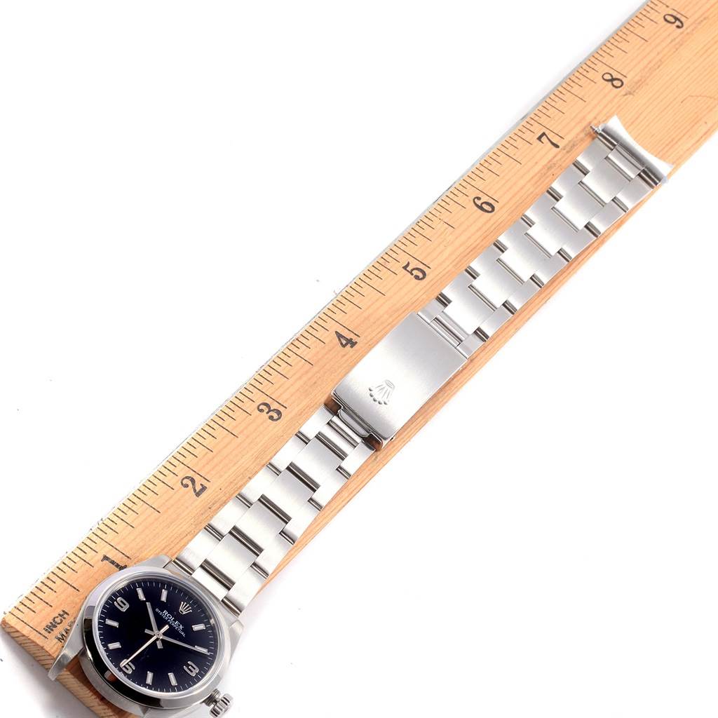 The image shows a top-down view of a Mid-Size Rolex watch with a stainless steel band next to a ruler.