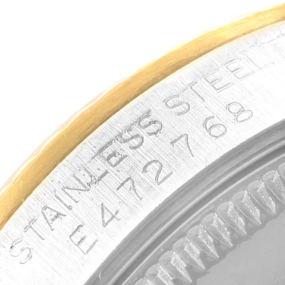 The image shows a close-up of the bezel and case side of a Mid-Size Rolex watch, highlighting the stainless steel material and engraved text.