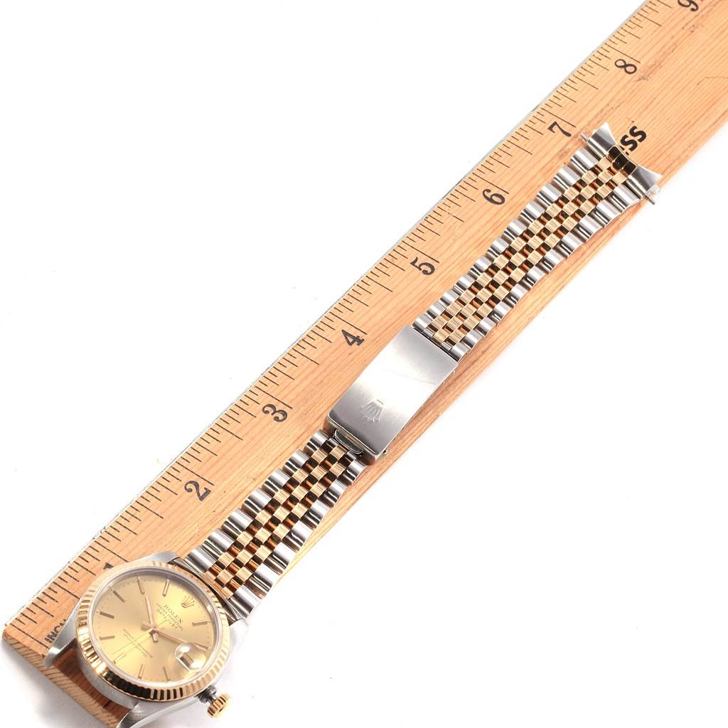 The Rolex Mid-Size 68273 Women's Steel and Gold (two tone) Champagne Dial 68273 Women's Steel and Gold (two tone) Champagne Dial watch is shown from a top view along with a wooden ruler, displaying the entire face, bracelet, and clasp.