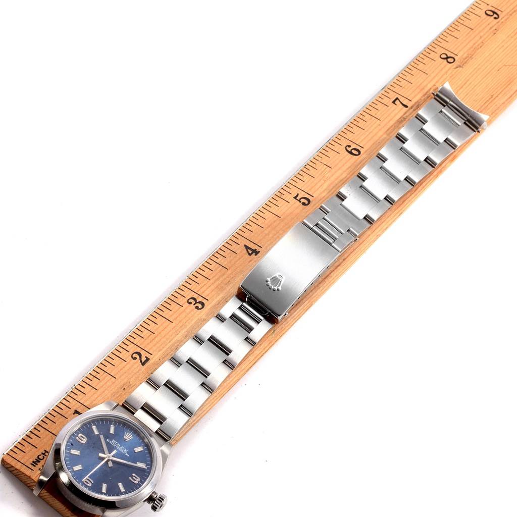 The image shows a Rolex Mid-Size 77080 Women's Stainless Steel Blue Dial 77080 Women's Stainless Steel Blue Dial watch laid flat next to a ruler, displaying its watch face, band, and clasp from an overhead angle.