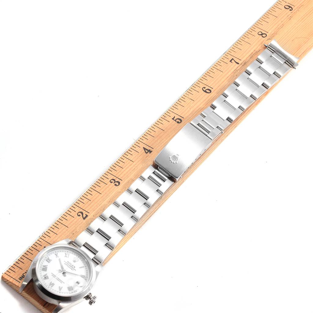 The image shows a Mid-Size Rolex watch laid flat next to a ruler, displaying its face, bracelet, and clasp.