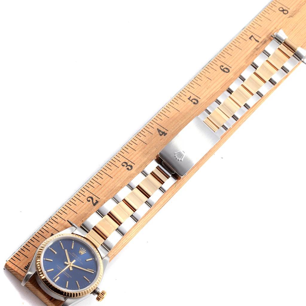 The image shows a Rolex Mid-Size 67513 Women's Steel and Gold (two tone) Blue Dial 67513 Women's Steel and Gold (two tone) Blue Dial model watch with a blue dial and two-tone metal bracelet, placed alongside a ruler.