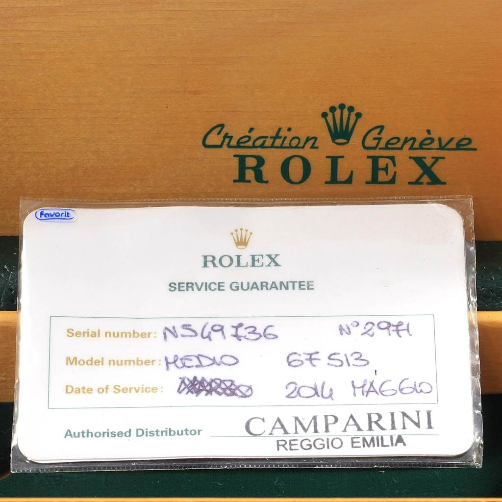 The image shows a Rolex service guarantee card with details about the Rolex Mid-Size 67513 Women's Steel and Gold (two tone) Blue Dial 67513 Women's Steel and Gold (two tone) Blue Dial model, placed against a Rolex packaging box.