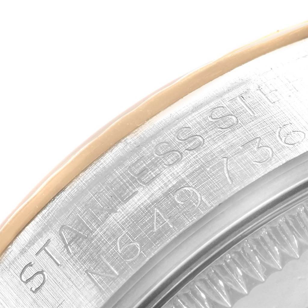 This close-up angle shows the stainless steel case back of a mid-size Rolex watch and part of the bezel.