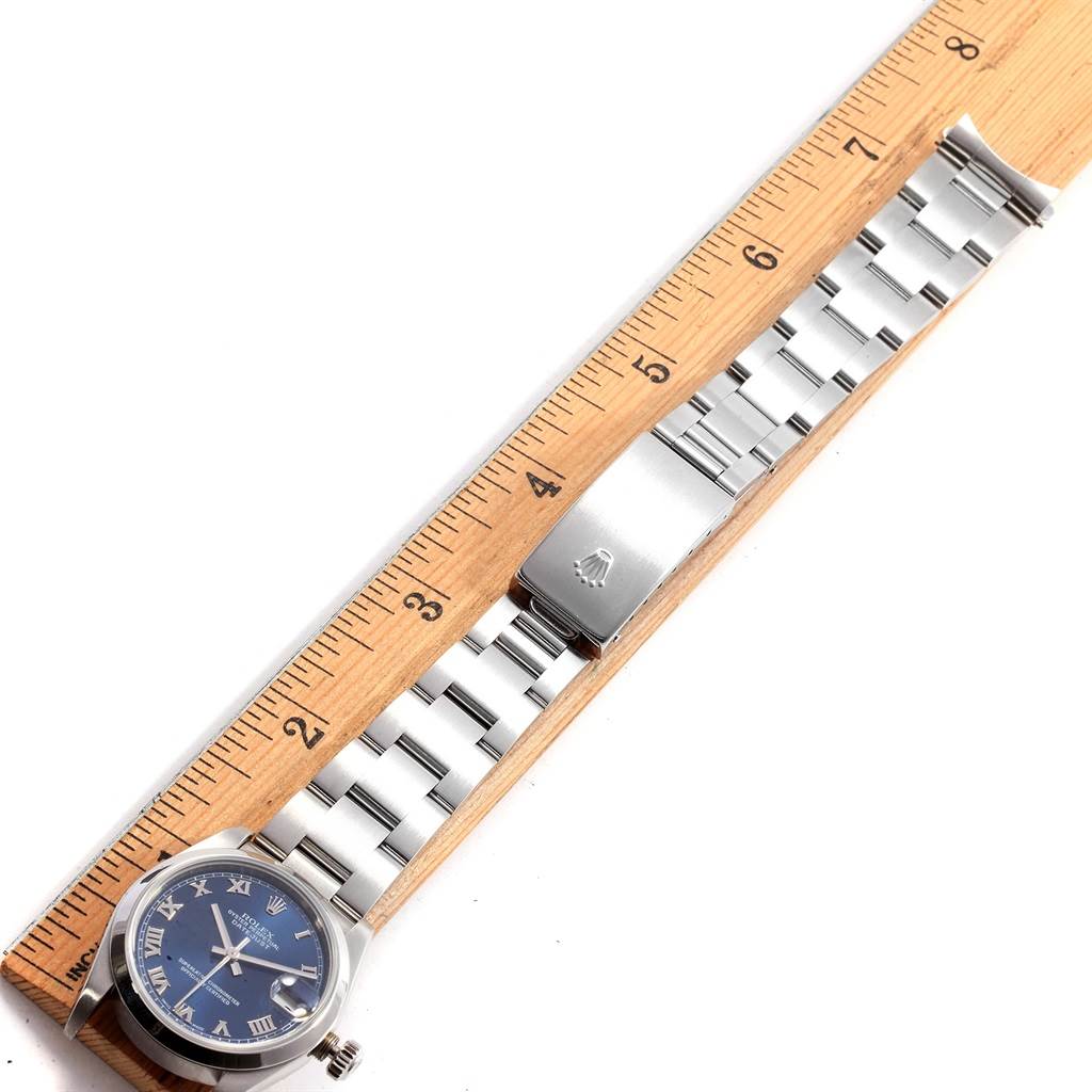 The Rolex Mid-Size 78240 Women's Stainless Steel Blue Dial 78240 Women's Stainless Steel Blue Dial watch is shown flat from above, highlighting the face, bracelet, and clasp next to a wooden ruler.