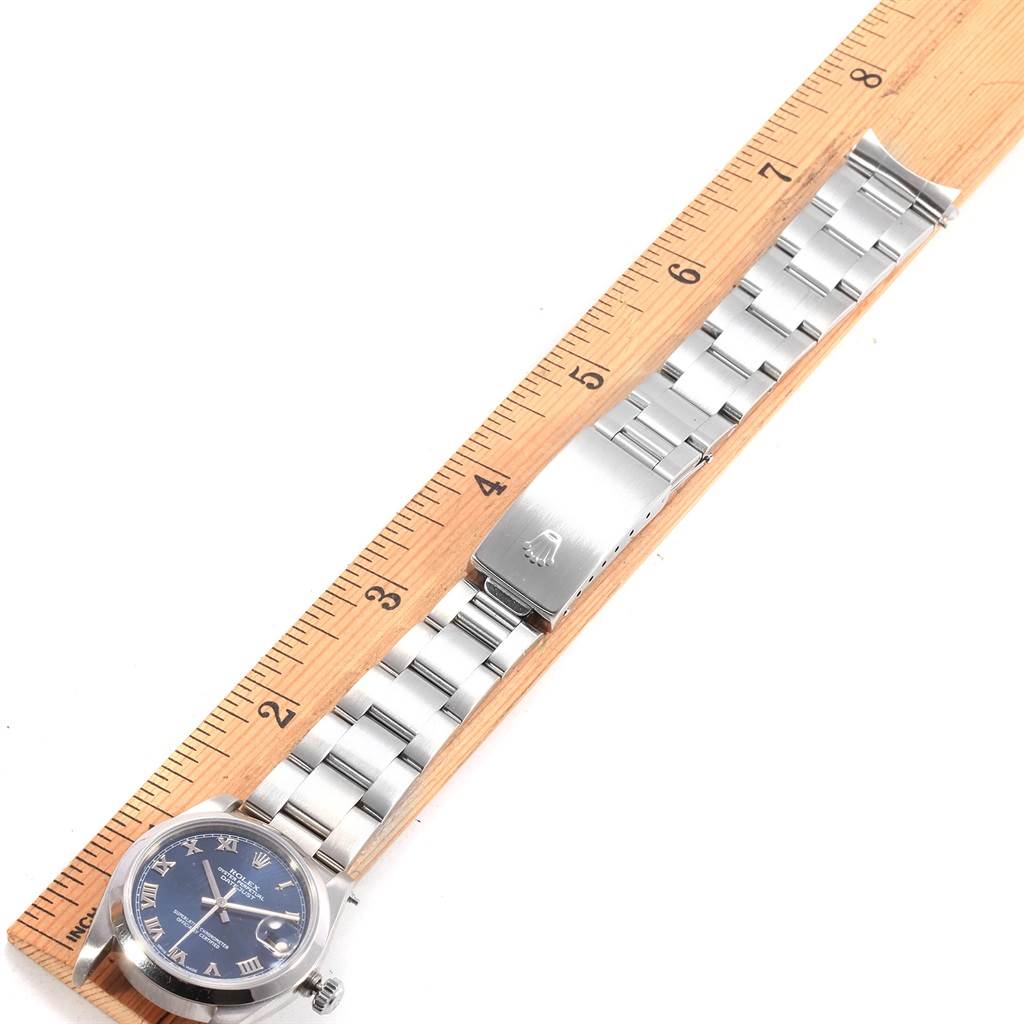 The Rolex Mid-Size 78240 Women's Stainless Steel Blue Dial 78240 Women's Stainless Steel Blue Dial watch is displayed flat on a wooden ruler, showcasing its bracelet, clasp, and dial.