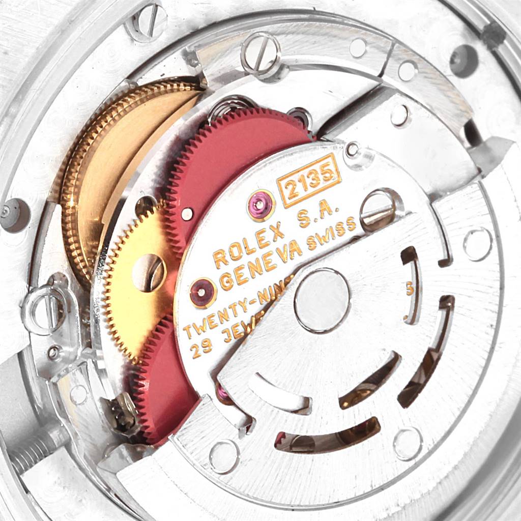 The image shows a close-up of the internal movement mechanism of a mid-size Rolex watch, highlighting the gears and rotor.