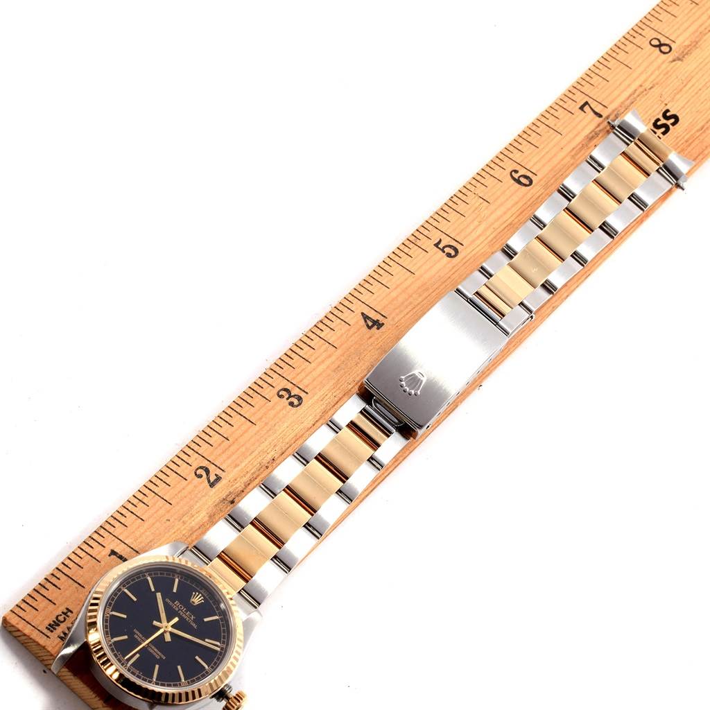 The image shows a Rolex Mid-Size 67513 Women's Steel and Gold (two tone) Black Dial 67513 Women's Steel and Gold (two tone) Black Dial watch placed next to a ruler, displaying the watch face, bezel, and metal bracelet with clasp.