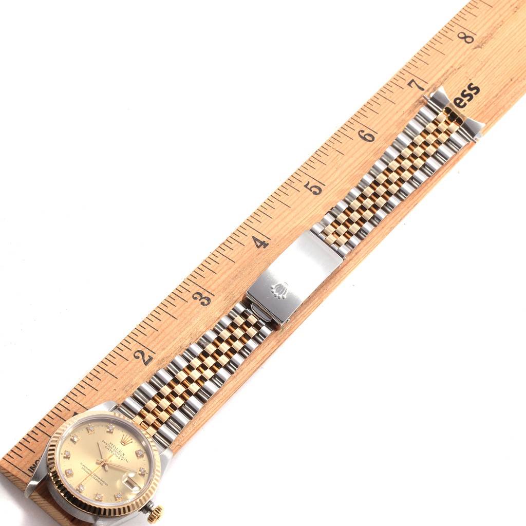 The image shows a top-down view of a Mid-Size Rolex watch, displaying the watch face, bracelet, and clasp beside a ruler.