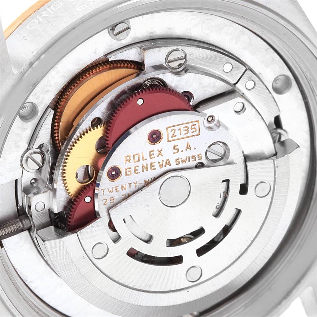 This image shows the mechanical movement components of a Mid-Size Rolex watch, including gears and the rotor.