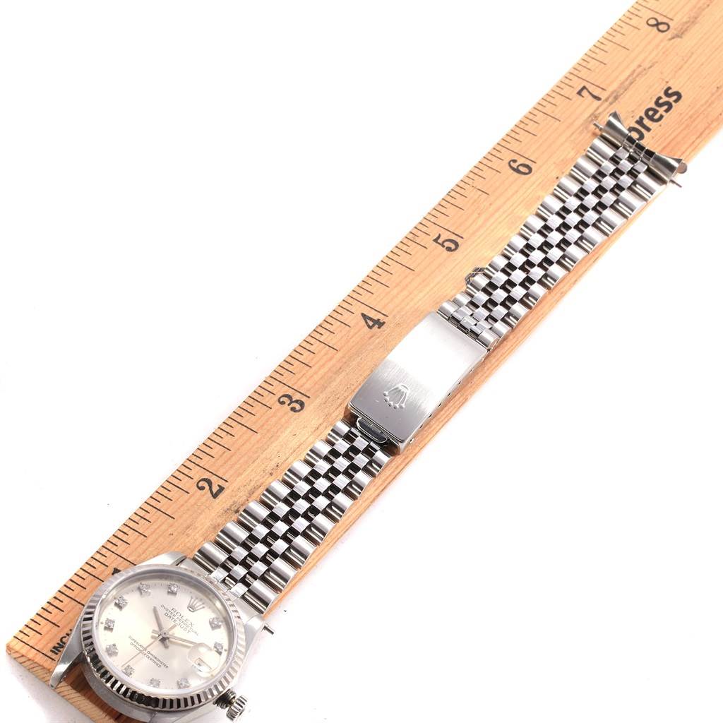 The image shows a top view of a Mid-Size Rolex watch and its band, placed next to a ruler for scale.