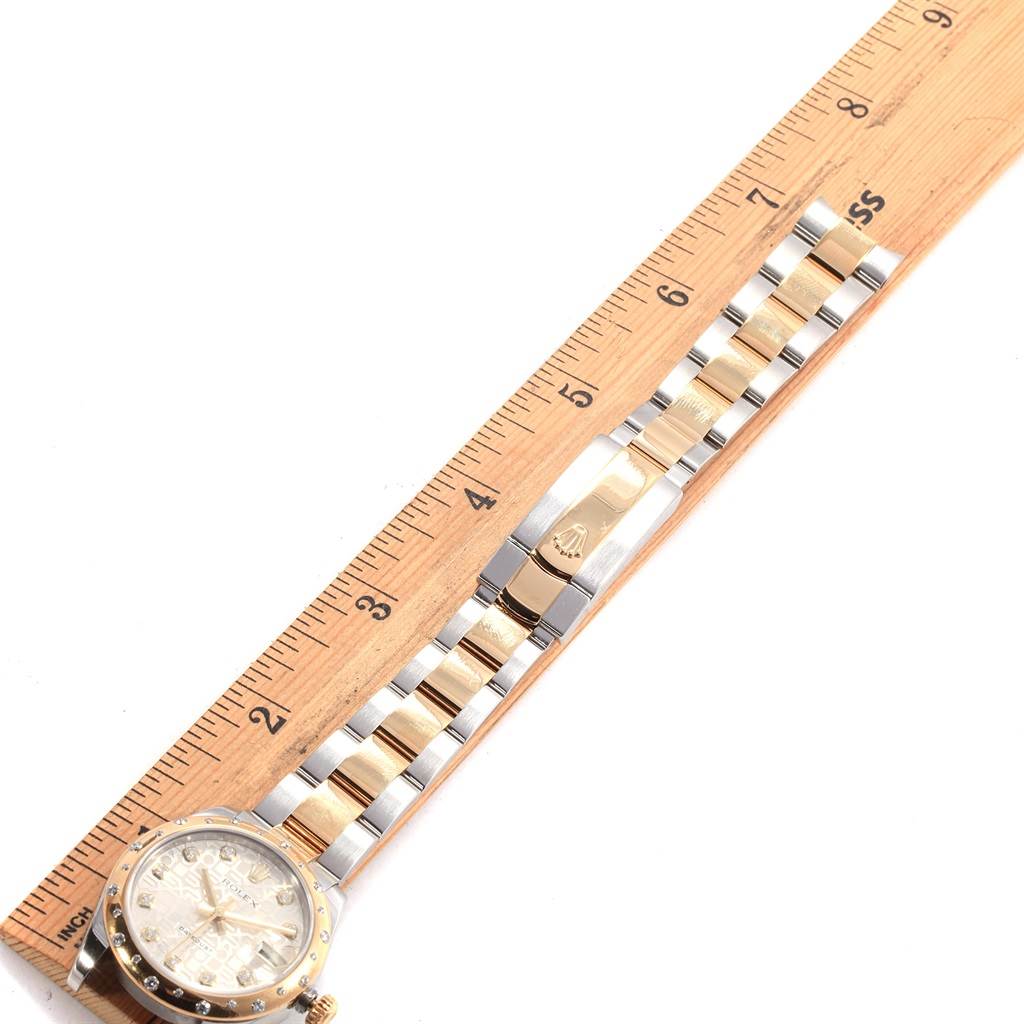 This image shows a Rolex Mid-Size 178343 Women's Steel and Gold (two tone) Silver Dial 178343 Women's Steel and Gold (two tone) Silver Dial model watch laid flat next to a ruler, highlighting its length and bracelet design.