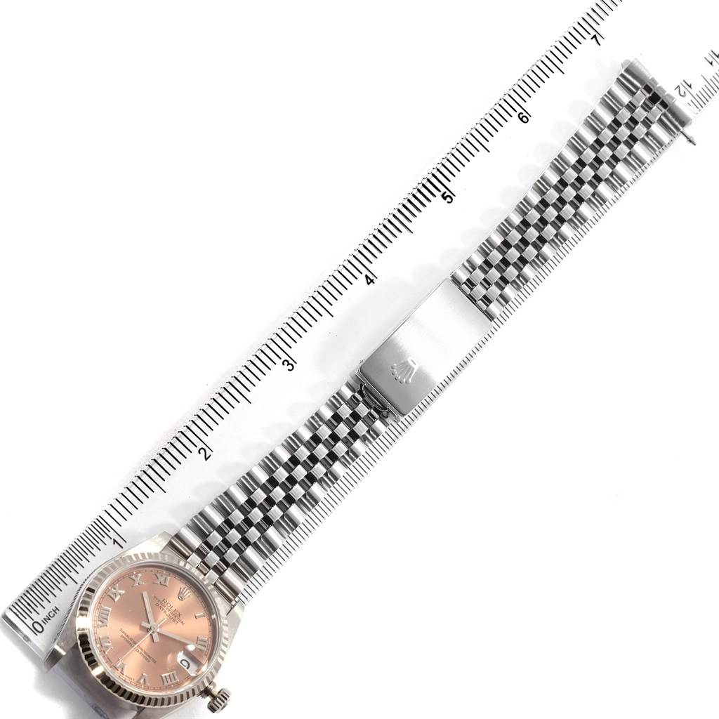 This image shows an overhead view of a Rolex Mid-Size 68274 Women's Stainless Steel Pink Dial 68274 Women's Stainless Steel Pink Dial watch with a metal bracelet and a ruler measuring its length.