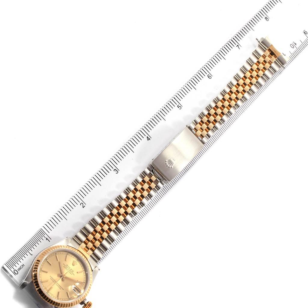 The Rolex Mid-Size 68273 Women
s Steel and Gold (two tone) Champagne Dial 68273 Women
s Steel and Gold (two tone) Champagne Dial watch is shown from a top-down angle, displaying its face, bracelet, and clasp alongside a ruler for measurement.