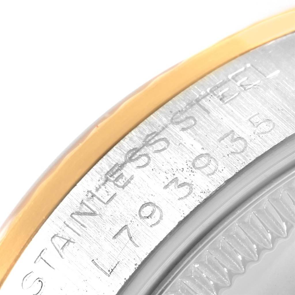 This close-up image of a Rolex Mid-Size 68273 Women
s Steel and Gold (two tone) Champagne Dial 68273 Women
s Steel and Gold (two tone) Champagne Dial watch shows part of the bezel and the engraving of "STAINLESS STEEL" with a serial number.