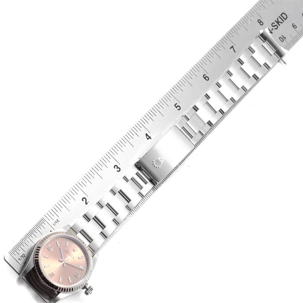 The image shows a top-down view of a Rolex Mid-Size 67514 Women
s Stainless Steel Pink Dial 67514 Women
s Stainless Steel Pink Dial model watch with its bracelet next to a ruler for size reference.