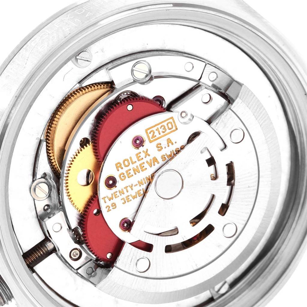 The image shows the internal mechanism of a Mid-Size Rolex watch with visible gears and jewels at a close-up angle.