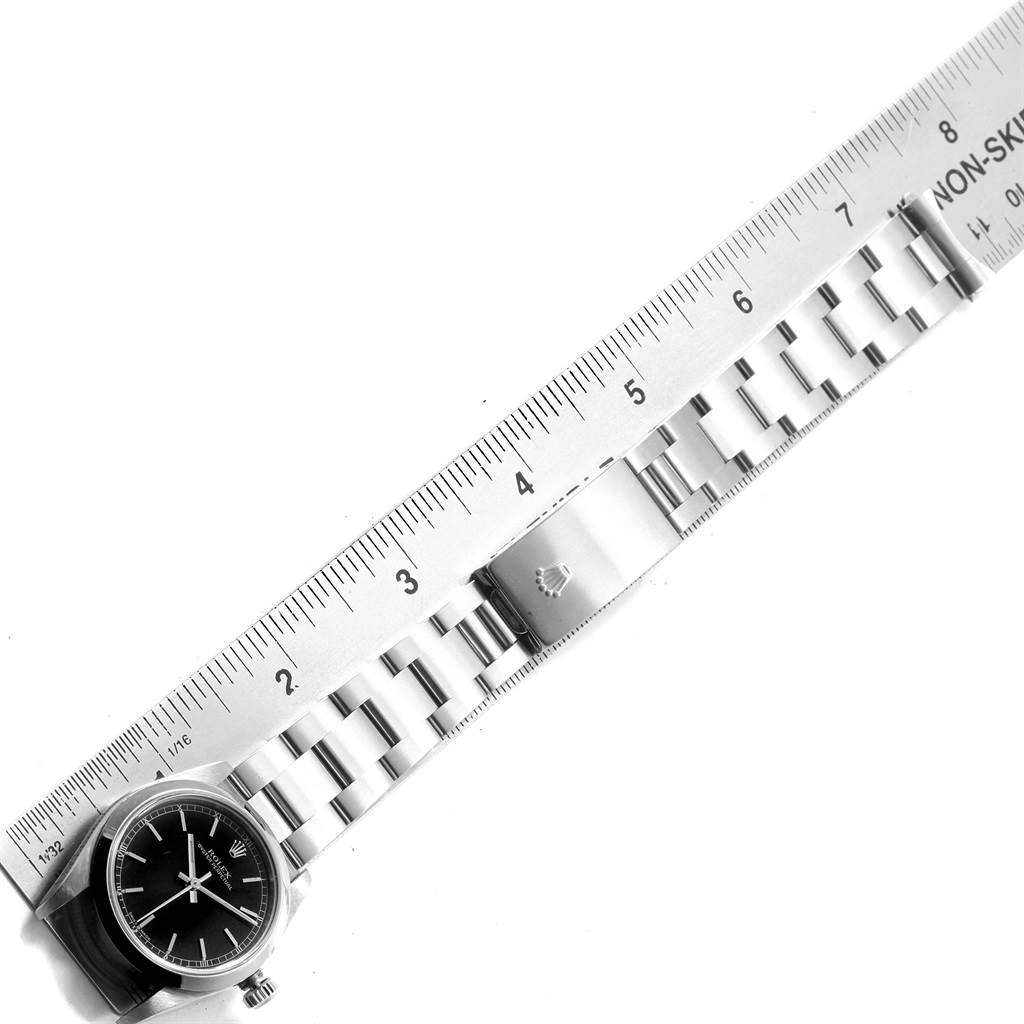 The image shows a top view of a mid-size Rolex watch, highlighting the face, bracelet, and clasp next to a ruler for scale.