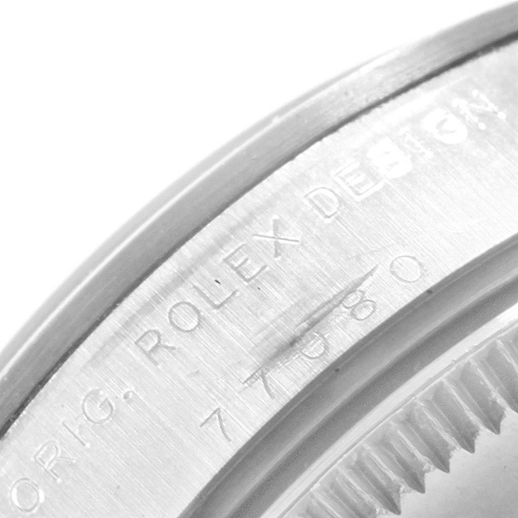 The image shows a close-up of the case side and bezel of a Rolex Mid-Size 77080 Women's Stainless Steel Black Dial 77080 Women's Stainless Steel Black Dial watch, featuring engraved text.