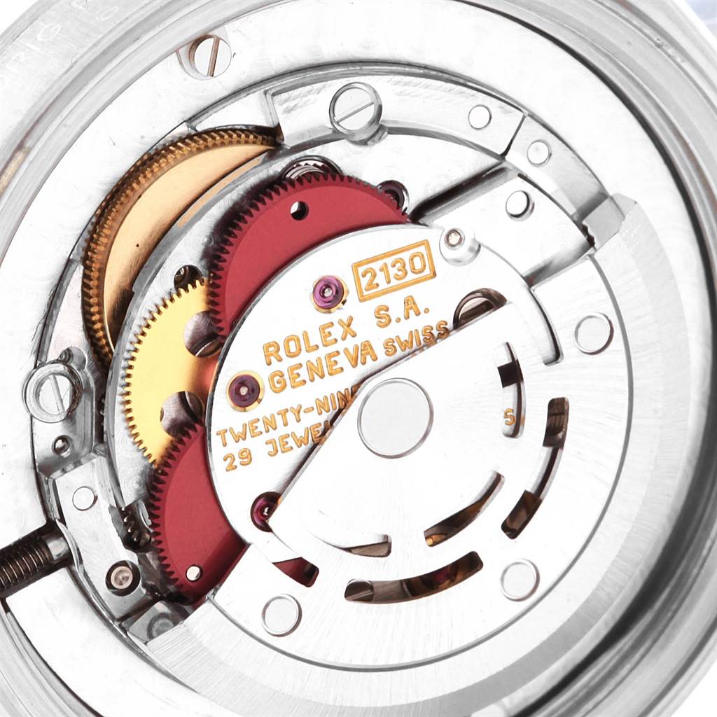 The image shows a close-up of the movement mechanism inside a Rolex Mid-Size 67480 Women's Stainless Steel Pink Dial 67480 Women's Stainless Steel Pink Dial watch, highlighting the gears and inscriptions.