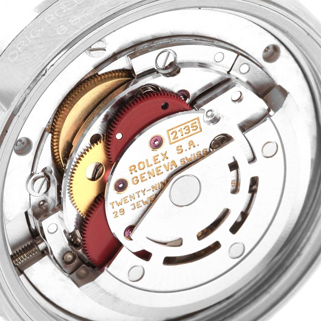 This image shows a close-up of the interior mechanical movement of a Rolex Mid-Size 68240 Women's Stainless Steel Blue Dial 68240 Women's Stainless Steel Blue Dial model, featuring its gears and inscriptions.