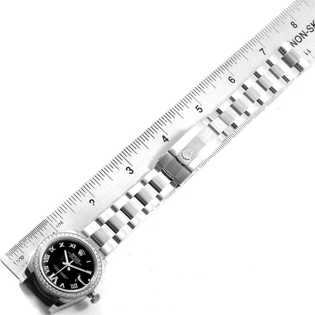 The image shows a Rolex Mid-Size 178384 Women's Stainless Steel Black Dial 178384 Women's Stainless Steel Black Dial watch and its band, laid flat next to a ruler, highlighting its length and design details.