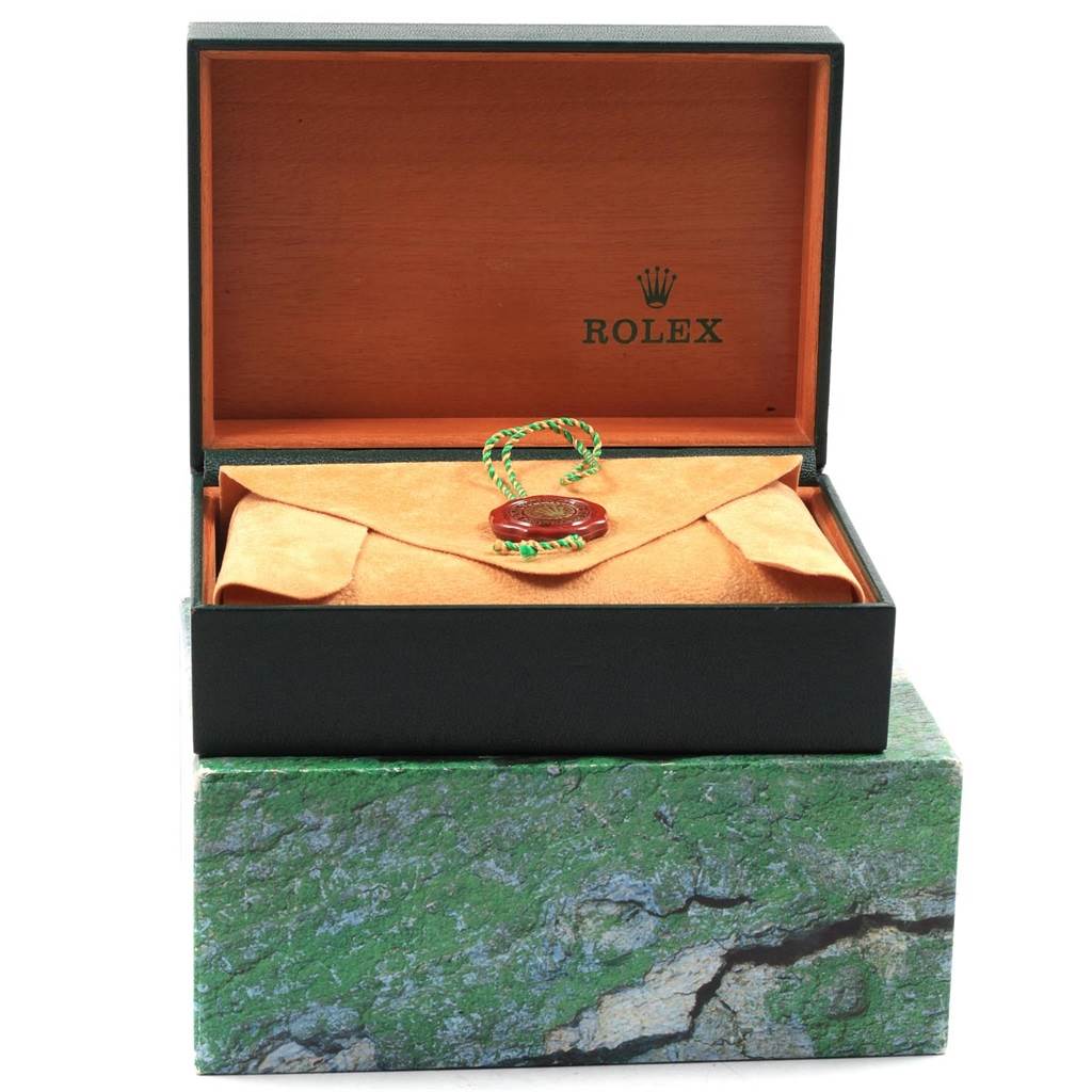 This image shows the packaging for a mid-size Rolex with an open wooden box, suede pouch, and green Rolex tag.