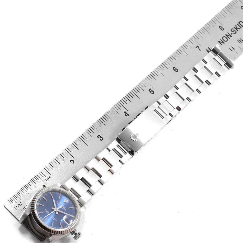 The image shows a top view of a Mid-Size Rolex watch with a blue dial and a silver bracelet positioned next to a ruler.