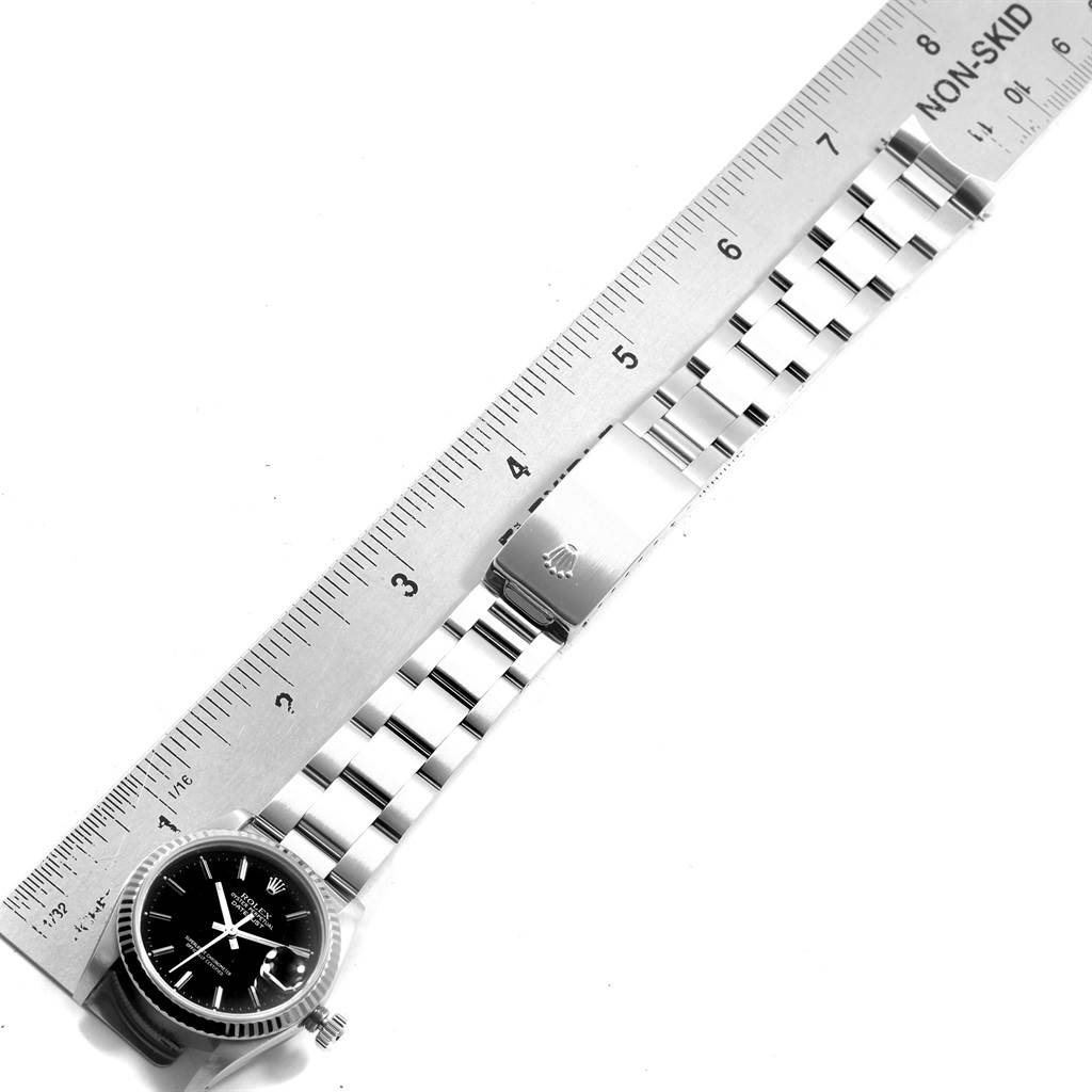 The image shows the top view of a Rolex Mid-Size 68274 Women's Stainless Steel Black Dial 68274 Women's Stainless Steel Black Dial watch displaying its face, bracelet, and clasp beside a ruler.