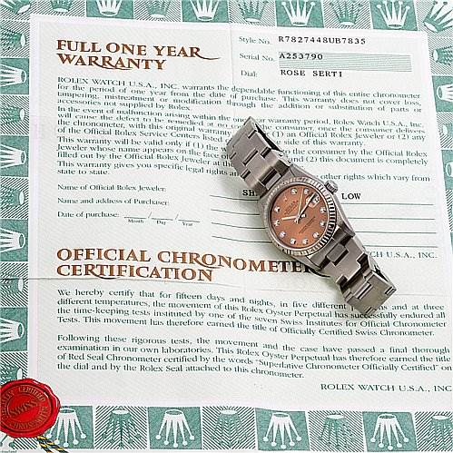 The image shows a Rolex Mid-Size 78274 Women's Stainless Steel Pink Dial 78274 Women's Stainless Steel Pink Dial watch placed on top of its warranty and official chronometer certification papers.