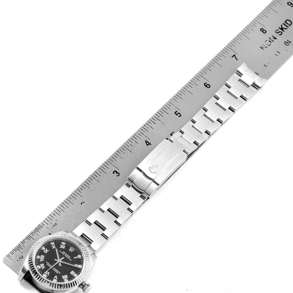 This image shows a Rolex Mid-Size 177234 Women's Stainless Steel Black Dial 177234 Women's Stainless Steel Black Dial model watch from above, featuring the watch face, bracelet, and clasp alongside a ruler.