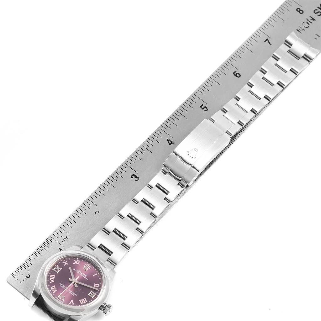 The image shows a side view of a Rolex Mid-Size 177200 Women's Stainless Steel Burgundy Dial 177200 Women's Stainless Steel Burgundy Dial watch with its metal bracelet alongside a ruler for scale.