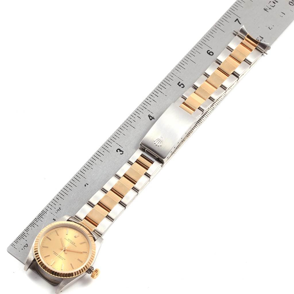 The image shows a top-down angle of a Rolex Mid-Size 67513 Women's Steel and Gold (two tone) Champagne Dial 67513 Women's Steel and Gold (two tone) Champagne Dial watch, highlighting the watch face, bracelet, clasp, and a ruler for scale.