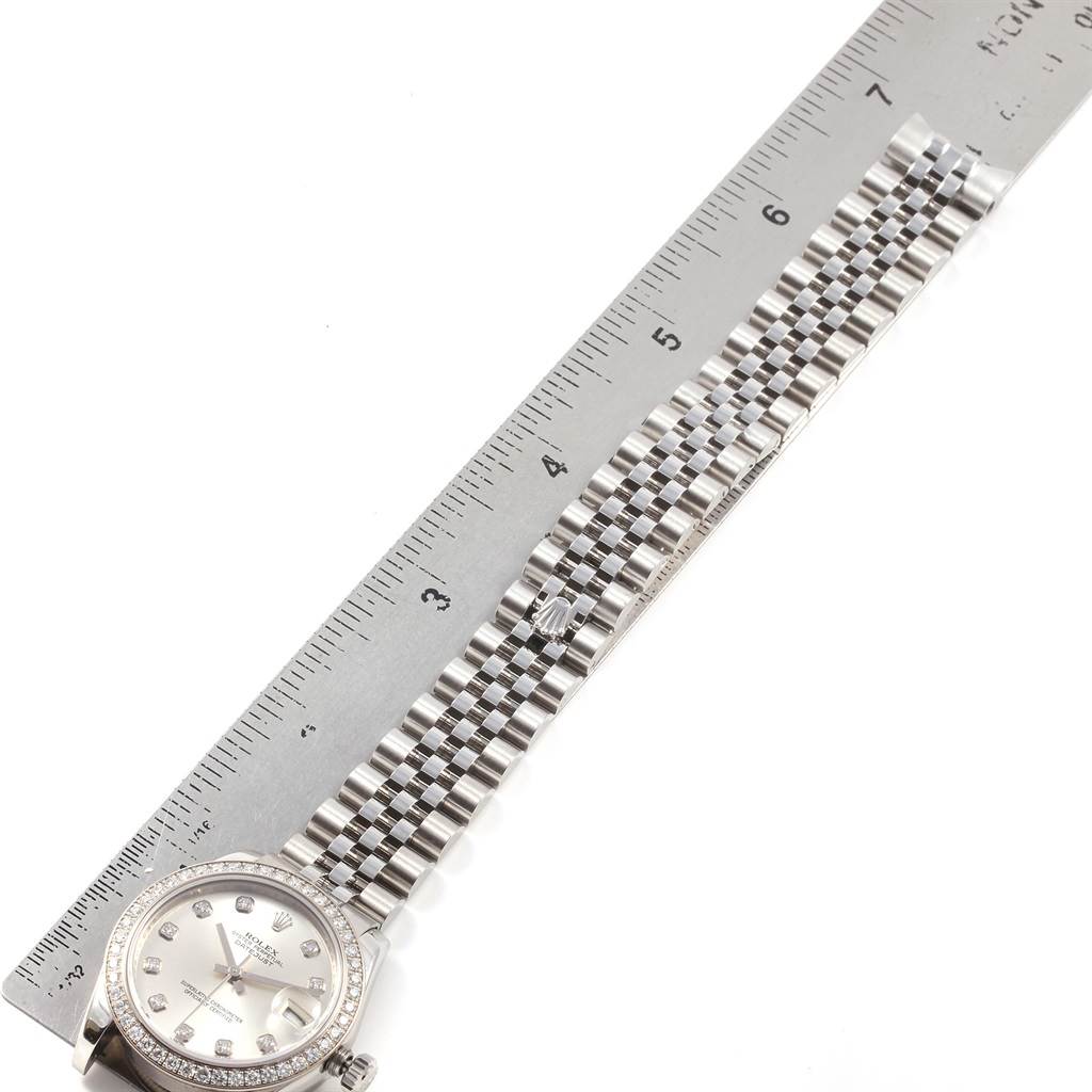 This image shows the face and bracelet of a Mid-Size Rolex watch, with a ruler indicating length.