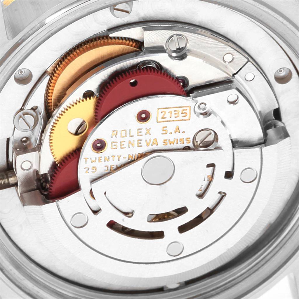 The image shows the intricate internal mechanics of a Rolex Mid-Size 68273 Women's Steel and Gold (two tone) Blue Dial 68273 Women's Steel and Gold (two tone) Blue Dial model watch, featuring gears and the engraved movement caliber "2135".