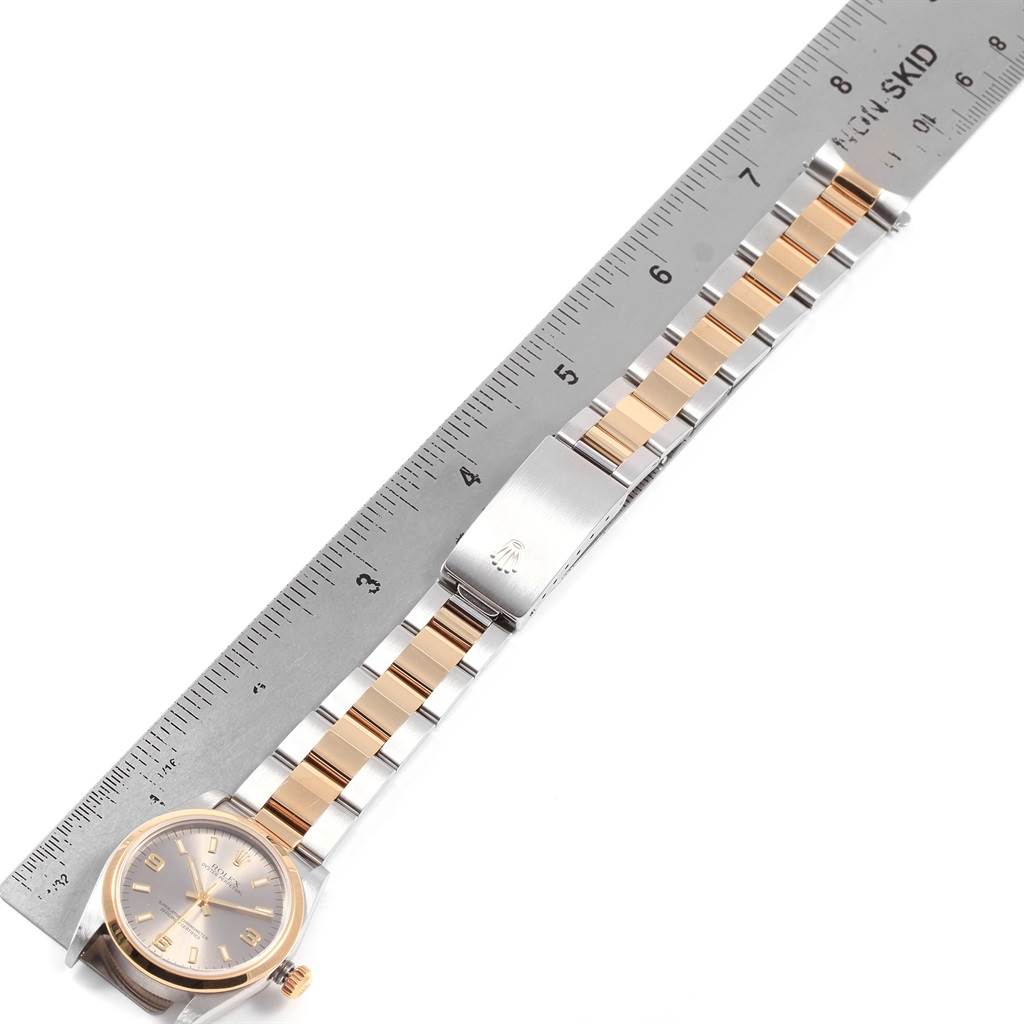 This Rolex Mid-Size 77483 Women's Steel and Gold (two tone) Grey Dial 77483 Women's Steel and Gold (two tone) Grey Dial watch is shown from a top-down angle, displaying its face, bracelet, and clasp alongside a metal ruler.