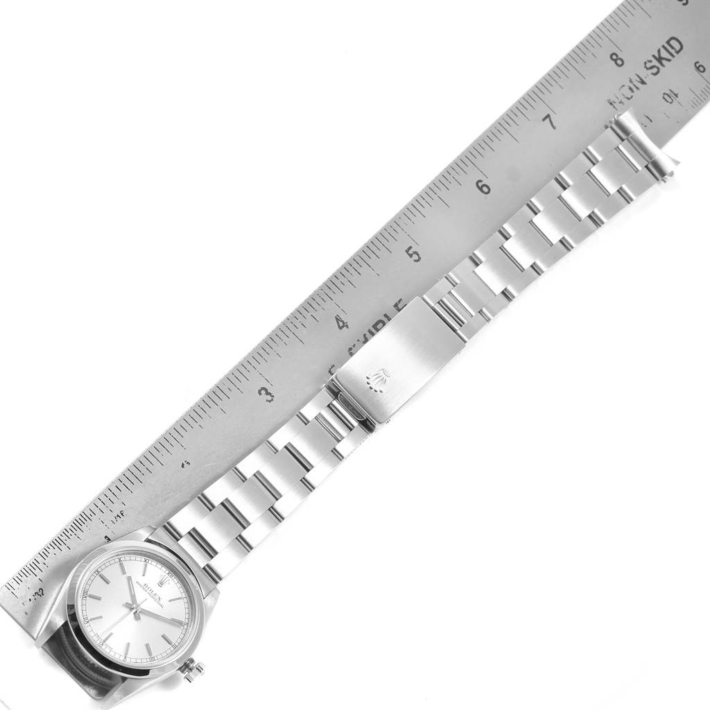 This image shows a Mid-Size Rolex watch laid flat adjacent to a ruler, with a clear view of its watch face, bracelet links, and clasp.