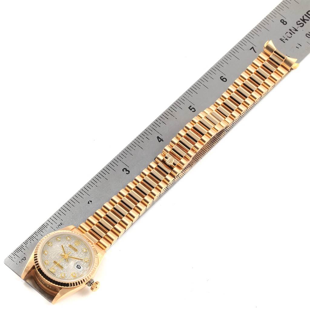 The image shows a flat lay of a Mid-Size Rolex watch with a golden bracelet next to a ruler for scale.