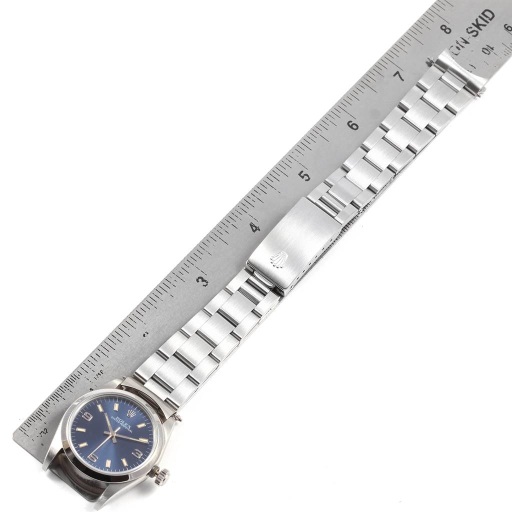 The Rolex Mid-Size 67480 Women's Stainless Steel Blue Dial 67480 Women's Stainless Steel Blue Dial model watch is shown at a slightly inclined angle, featuring its blue dial, case, bracelet, and clasp alongside a ruler.