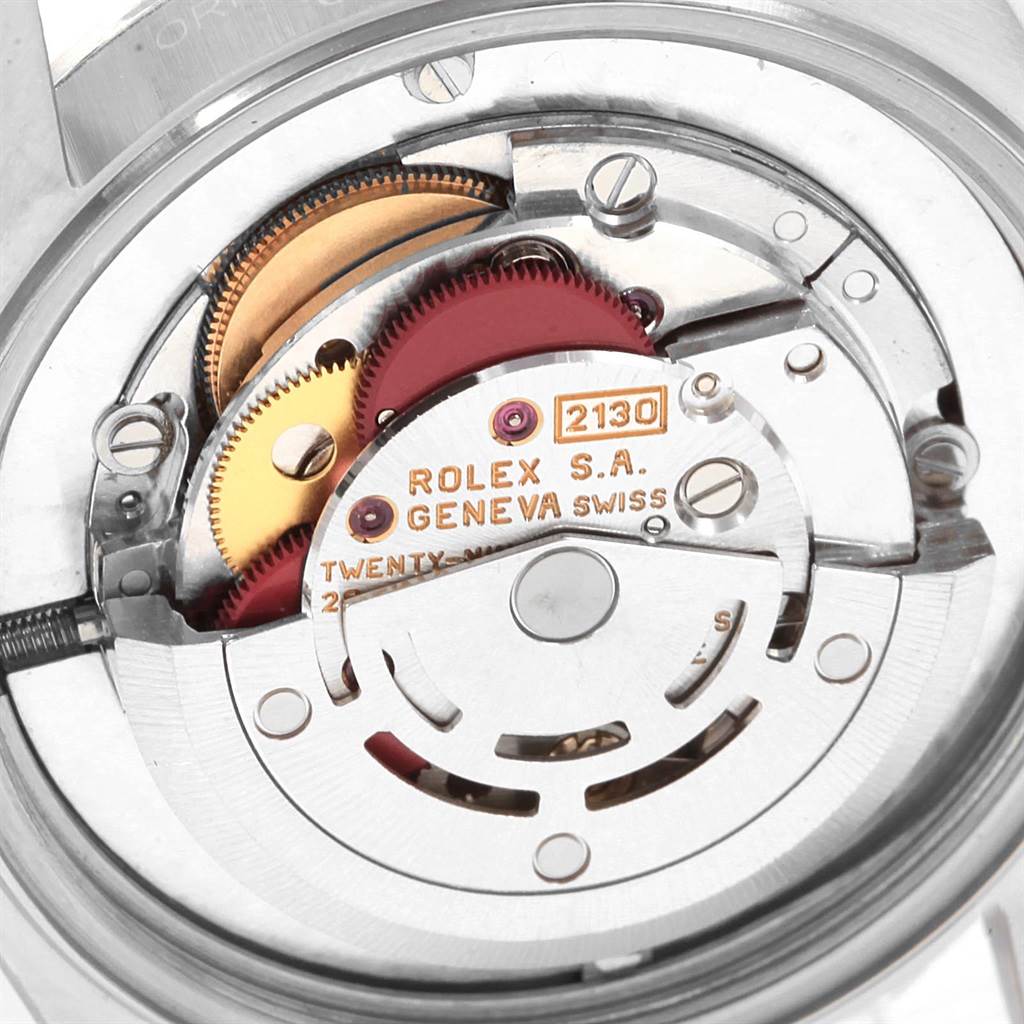 The image shows the movement mechanism of a mid-size Rolex with visible gears and inscriptions.