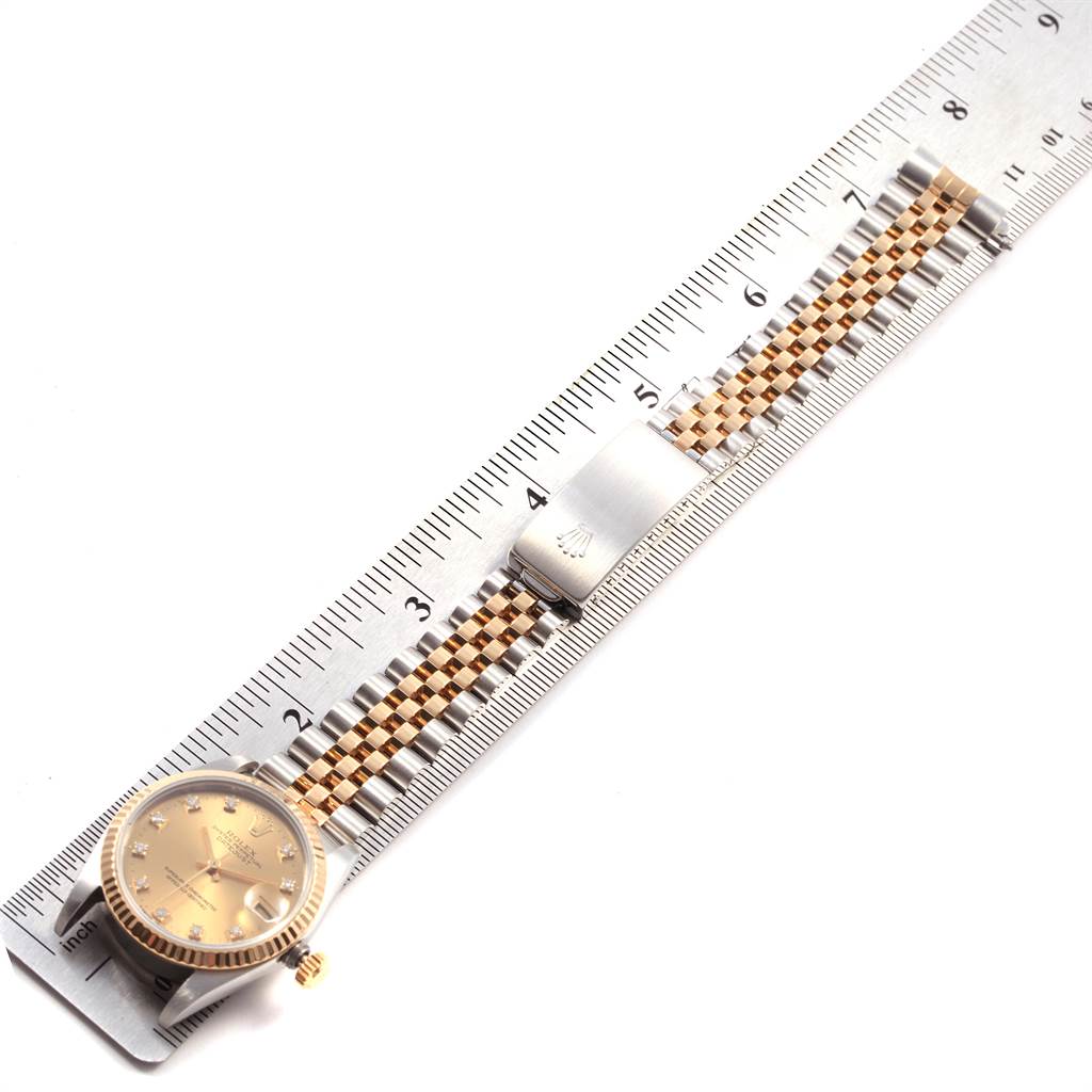 The Rolex Mid-Size 68273 Women's Steel and Gold (two tone) Champagne Dial 68273 Women's Steel and Gold (two tone) Champagne Dial watch is shown from an overhead angle, displaying the face, band, and clasp next to a ruler for scale.