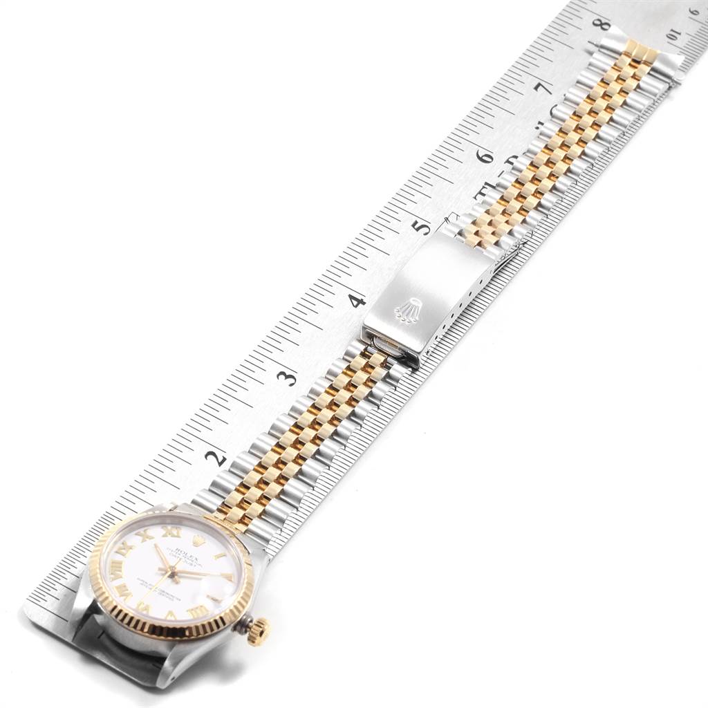 The watch face, crown, and part of the bracelet of the Rolex Mid-Size 68273 Women's Steel and Gold (two tone) White Dial 68273 Women's Steel and Gold (two tone) White Dial model are shown at an angle, positioned next to a ruler.