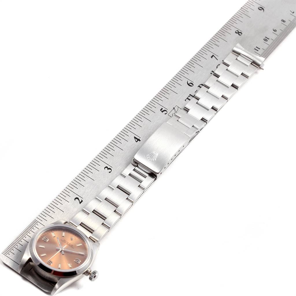 This image shows a Rolex Mid-Size 67480 Women
s Stainless Steel Pink Dial 67480 Women
s Stainless Steel Pink Dial watch, featuring the face, bracelet, and clasp, with a ruler for scale.