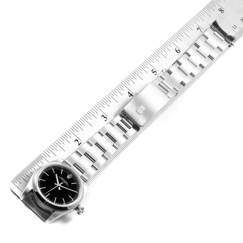 This image shows a Rolex Mid-Size 77080 Women's Stainless Steel Black Dial 77080 Women's Stainless Steel Black Dial watch laid against a ruler, displaying 5 inches of its bracelet and part of its clasp.