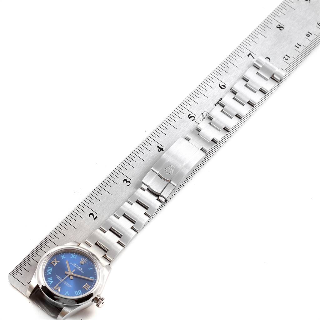 The image shows a Mid-Size Rolex watch laid flat next to a ruler, displaying the face, bracelet, and clasp.