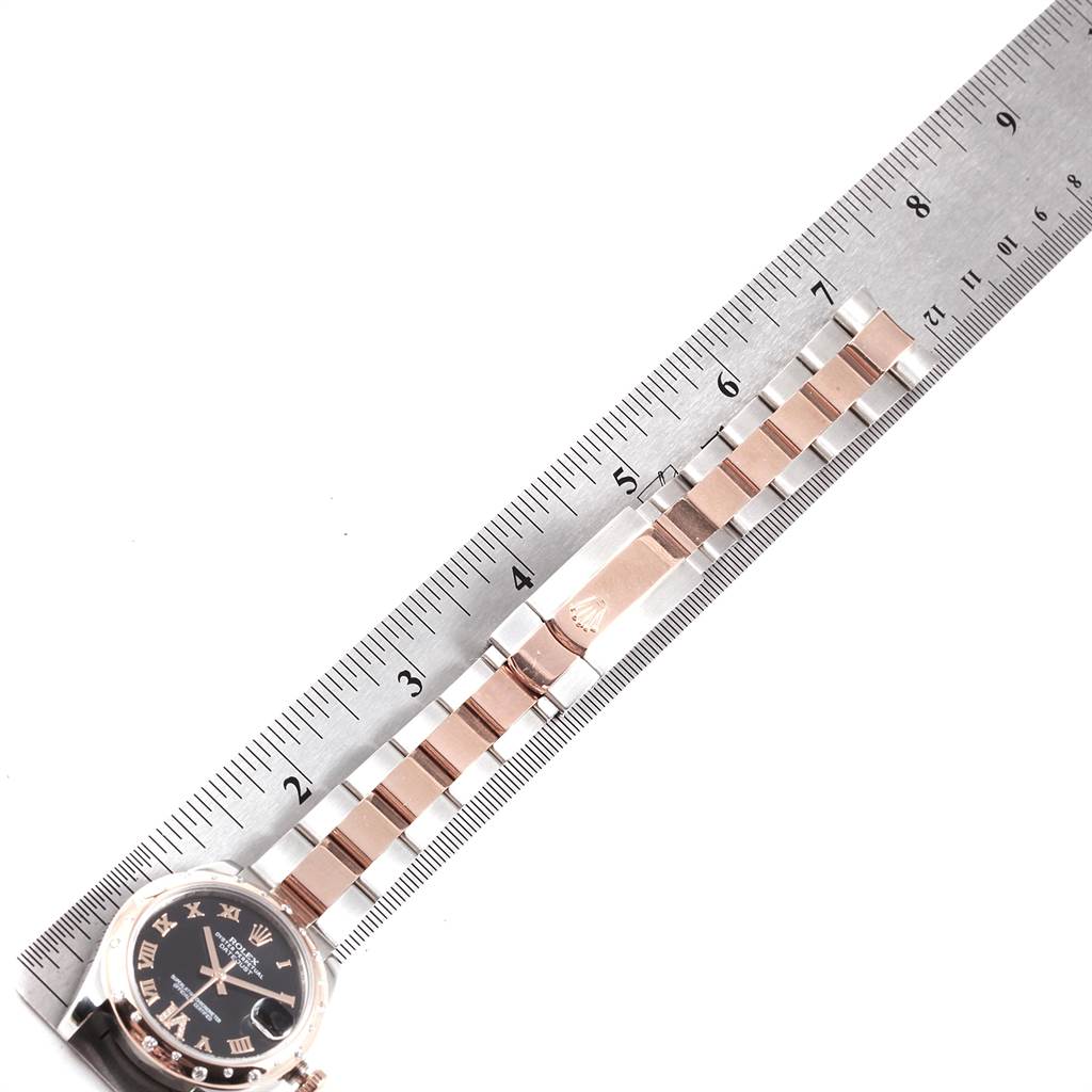 The image shows a side angle view of a Rolex Mid-Size 178341 Women's Steel and Gold (two tone) Black Dial 178341 Women's Steel and Gold (two tone) Black Dial model displaying the watch face and part of the bracelet placed along a ruler.