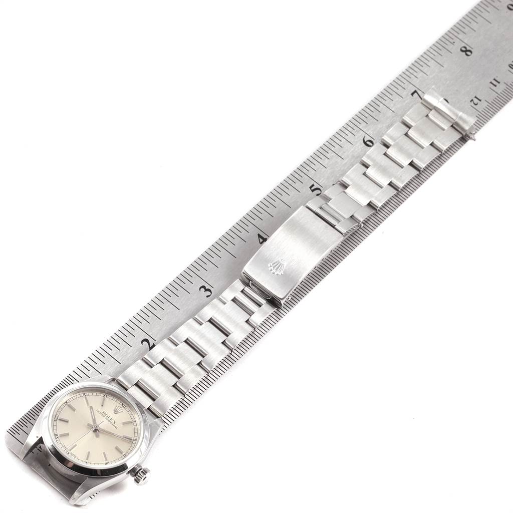 The image shows a Mid-Size Rolex watch laid next to a ruler, displaying the watch face, bracelet, and clasp from an aerial view.