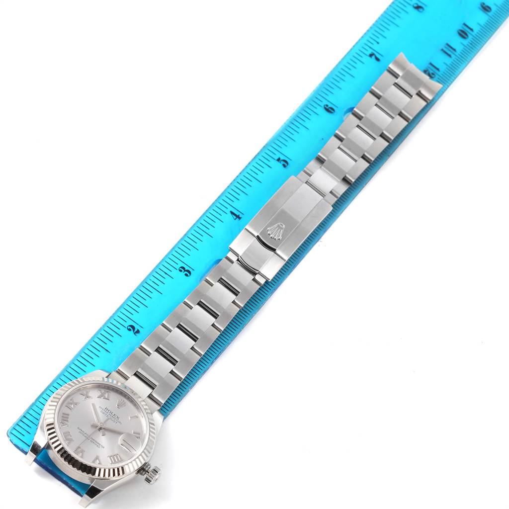 The image shows a fully extended Rolex Mid-Size 178274 Women's Stainless Steel Silver Dial 178274 Women's Stainless Steel Silver Dial model watch placed next to a measuring ruler, displayed from an overhead angle.